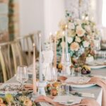 Eine festlich gedeckte Hochzeitstafel zeigt Kerzen, Glaswaren, Obst und florale Arrangements in zarten Rosé- und Cremetönen.