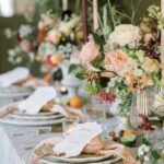 Festlich gedeckte Tafel mit Blumenarrangements, Kerzen und feinem Geschirr in sanften Pastelltönen.
